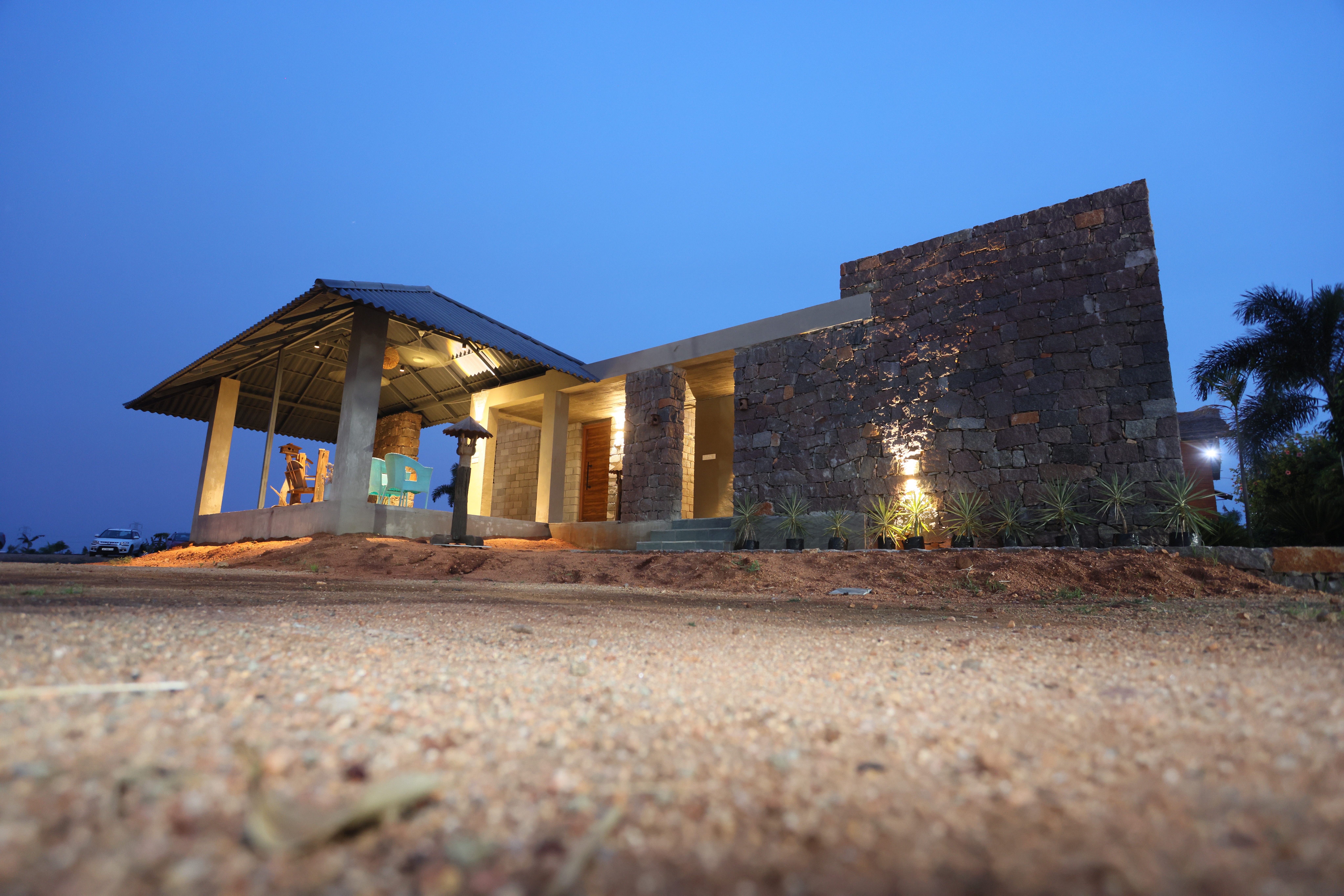 A modern stone farmhouse illuminated at dusk.
